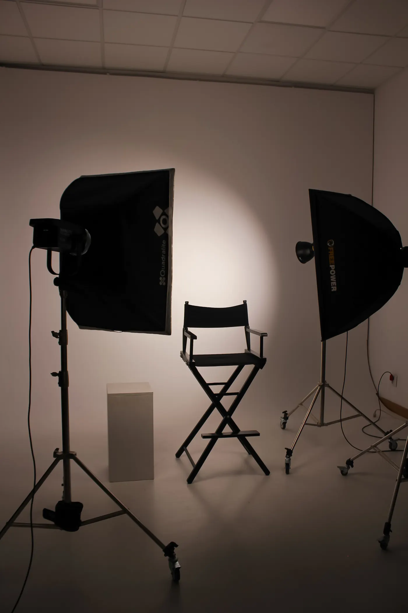 An empty photography studio with lighting stands and a director's chair.
